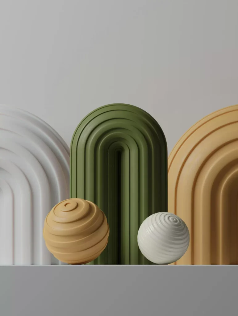 Three arched structures in white, green, and beige stand behind two spherical objects with spiral grooves, one beige and one white, on a plain gray surface.